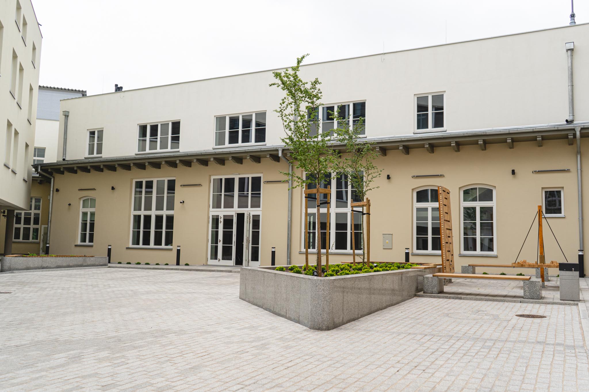 Budynek Muzeum Archeologicznego i Etnograficznego w Łodzi  po modernizacji. Odnowiona elewacja, kostka brukowa oraz gazon z roślinami. 
