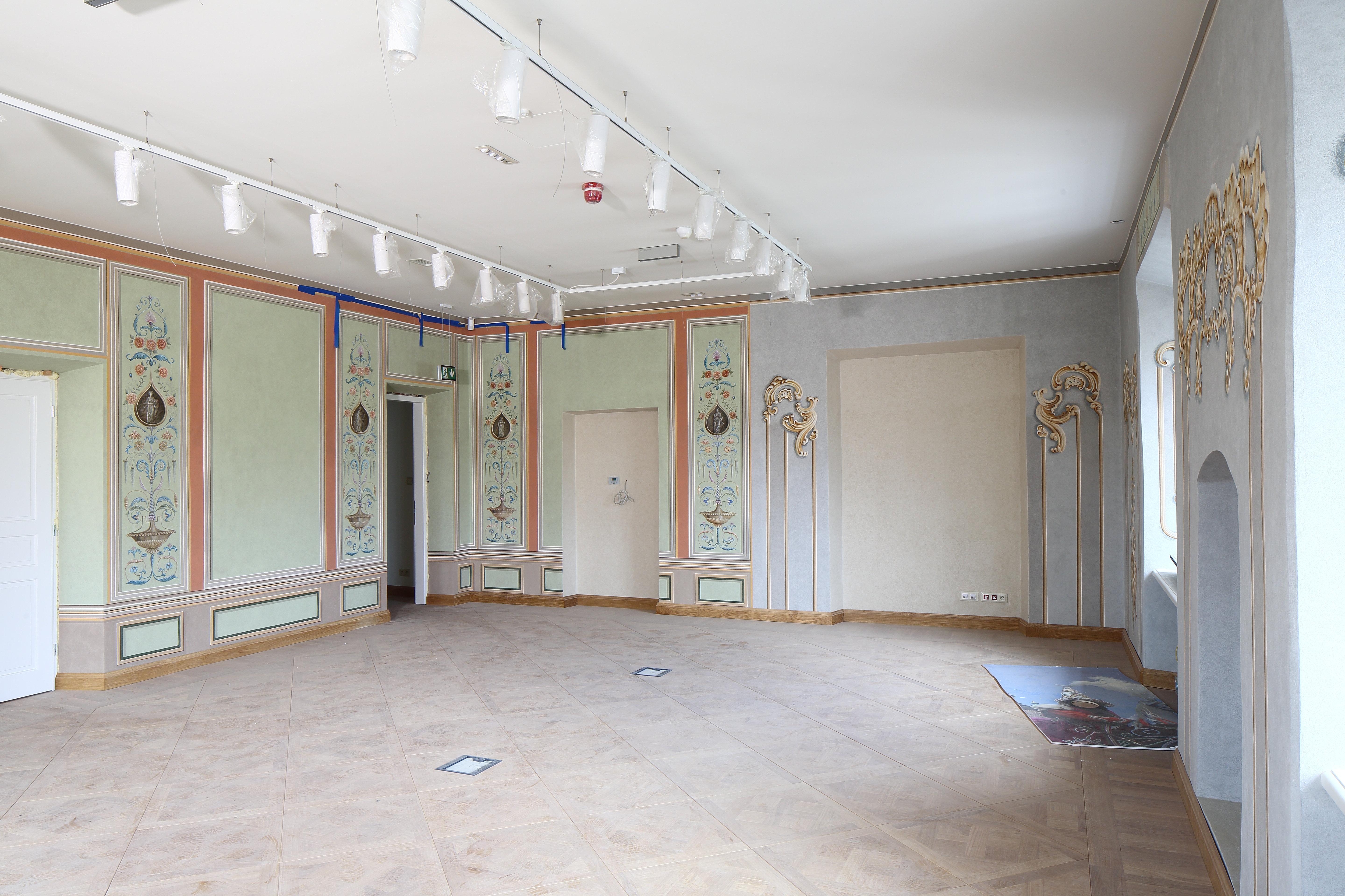 Wnętrze Pałacu Krzysztofory, puste pomieszczenie, ściany zdobione malowidłami. Na podłodze duże płytki